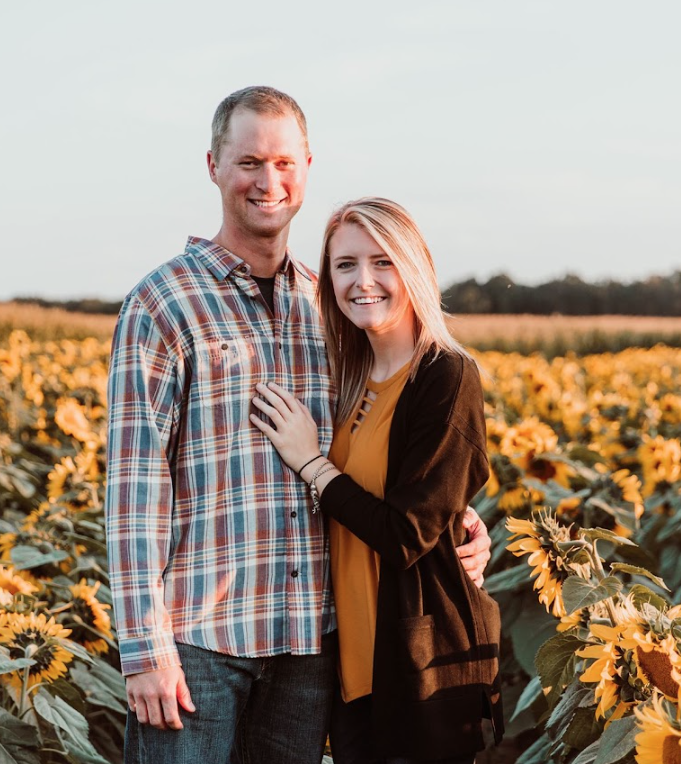 Conner and Kelsey stand in a field of sunflowers